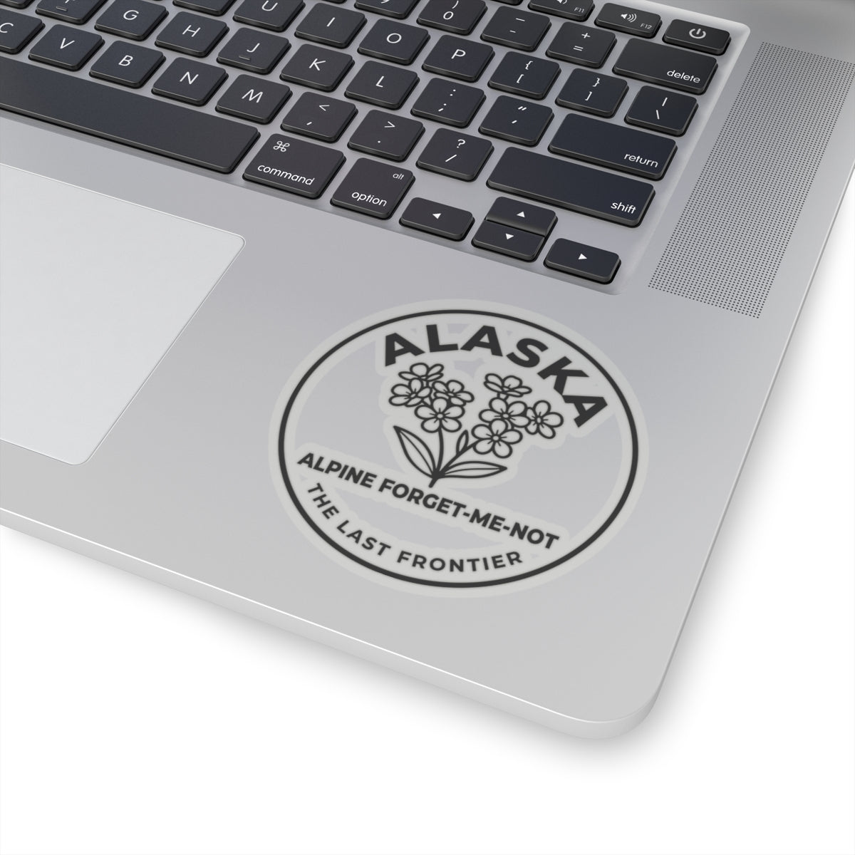 Alaska alpine forget-me-not vinyl sticker on laptop, round emblem with “ALASKA”