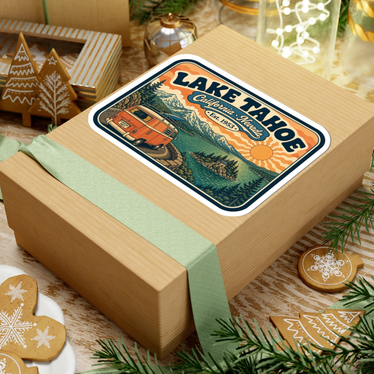 Kiss-cut Lake Tahoe sticker on a gift box, orange camper van and evergreen mountain lake scene.