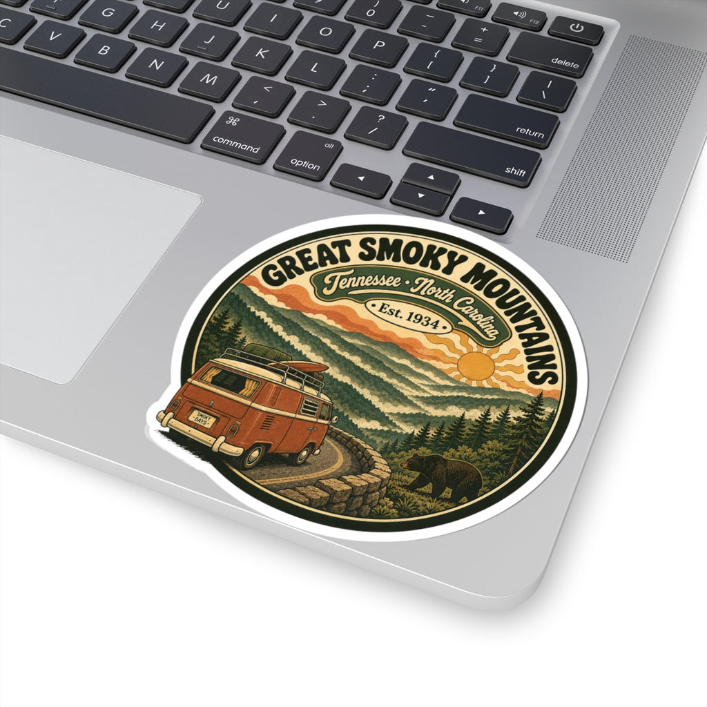 Round kiss-cut sticker featuring a retro camper van on a path through evergreen mountains