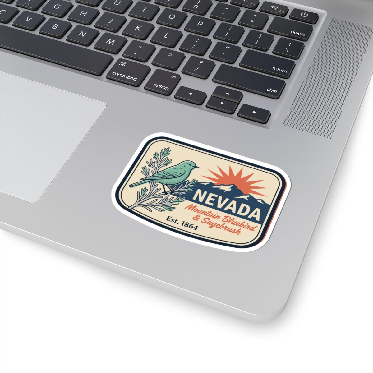 Nevada vintage state sticker with bluebird and sagebrush on a laptop surface, Est. 1864.