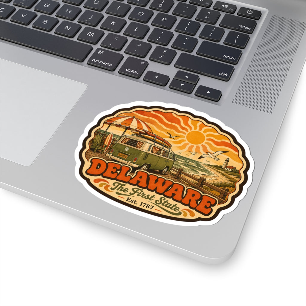 Oval kiss-cut Delaware sticker on laptop keyboard, showing vintage van and shoreline scene