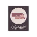 Mauve Nebraska metal wall art with oval landscape silhouette and 'Nebraska' script