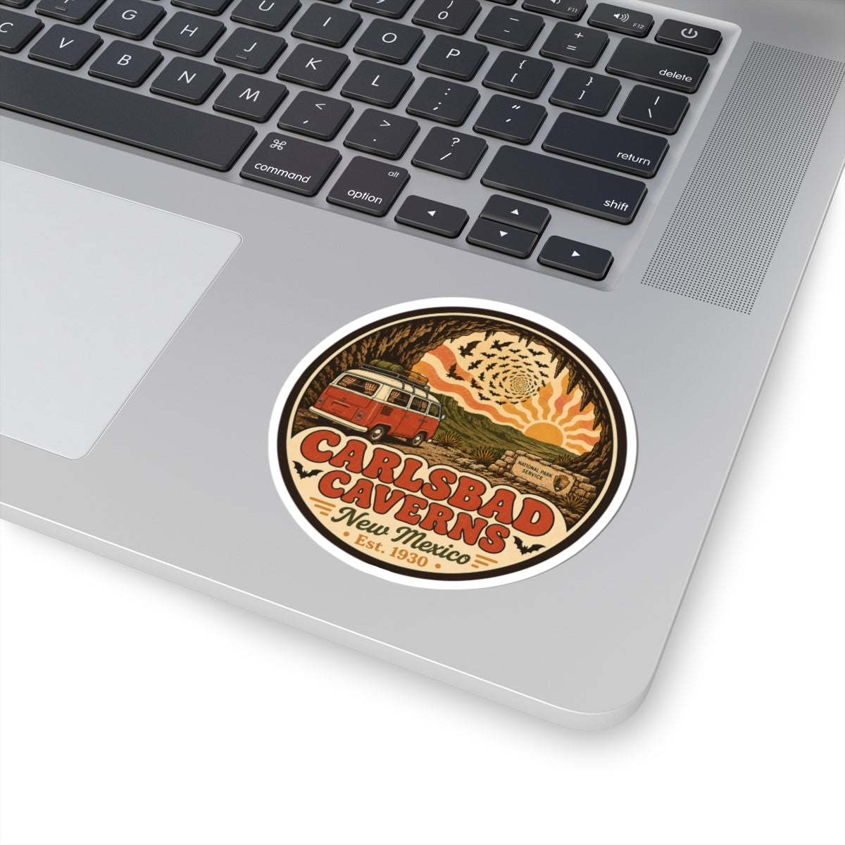 Small round Carlsbad Caverns sticker on a laptop keyboard; orange camper van in cave scene