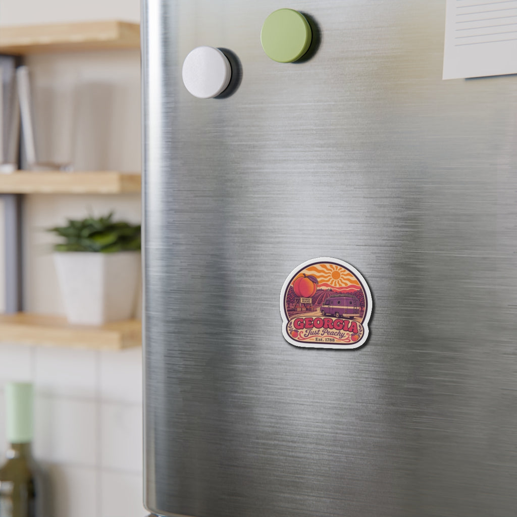 Die-cut magnet on stainless fridge door, round white border with 'GEORGIA' peach/van design