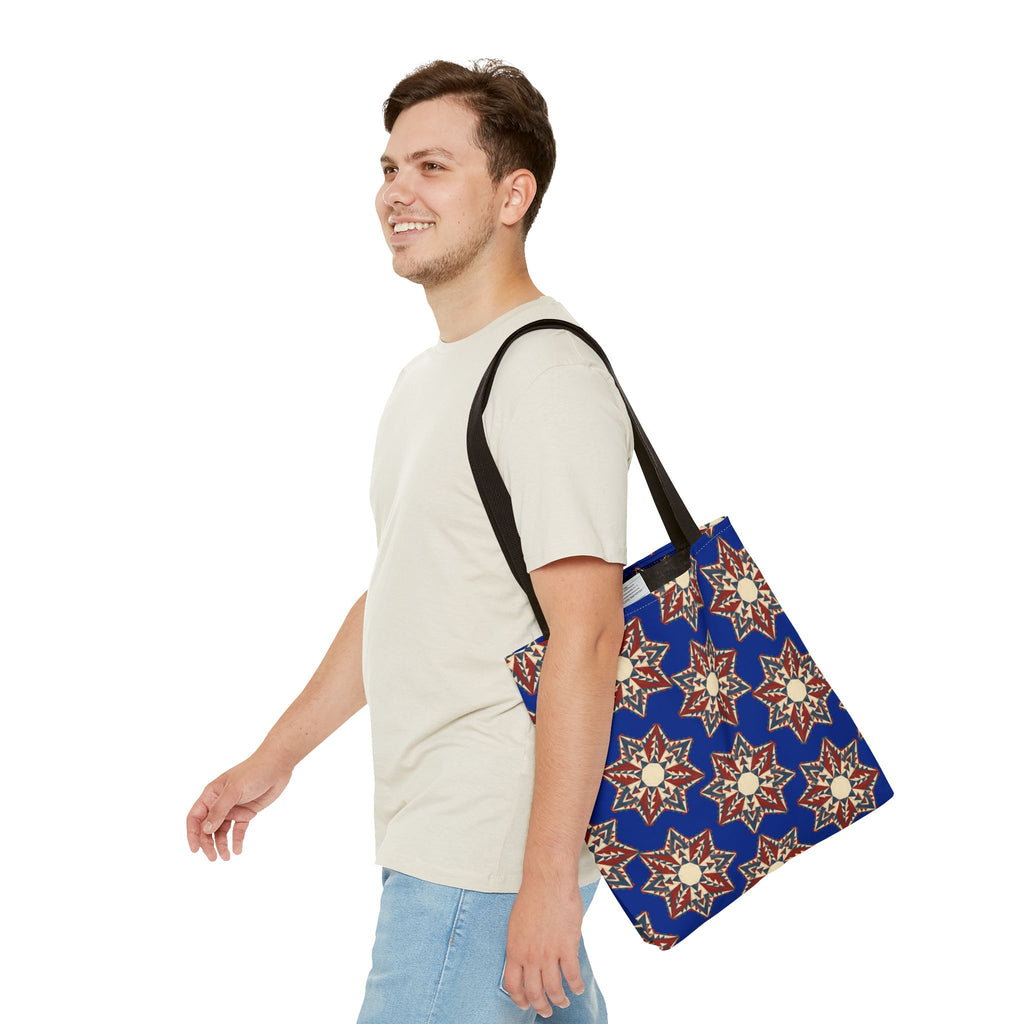 Blue tote bag with starburst floral mandala pattern and black shoulder straps, side view