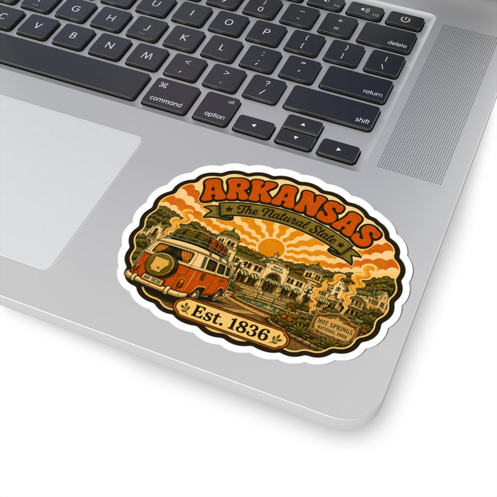 Round Arkansas travel sticker with orange camper van and “Est. 1836” on laptop