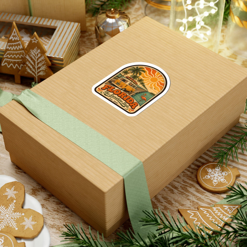 Florida sticker on wrapped gift box, with retro surf bus, palm trees, and flamingo