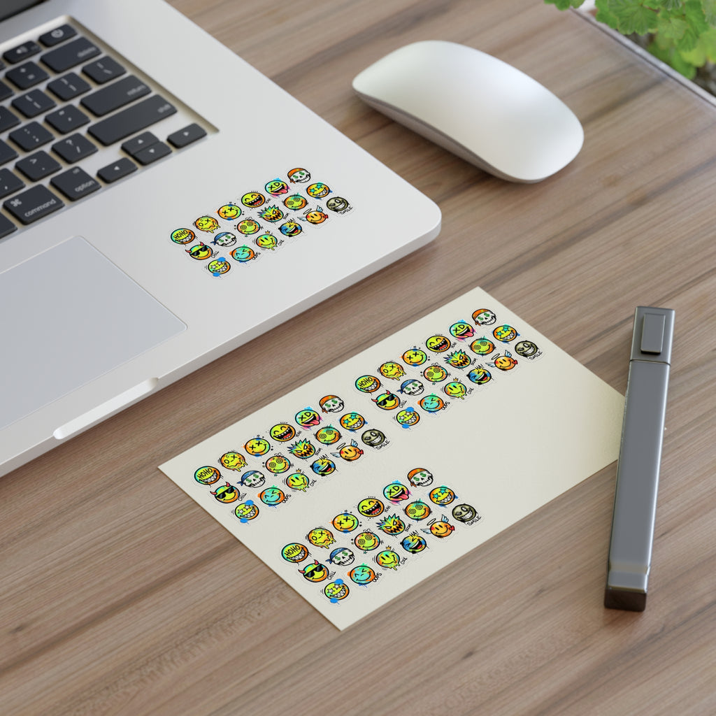 Emoji face sticker sheet (die-cut) with small faces on paper, on desk near laptop