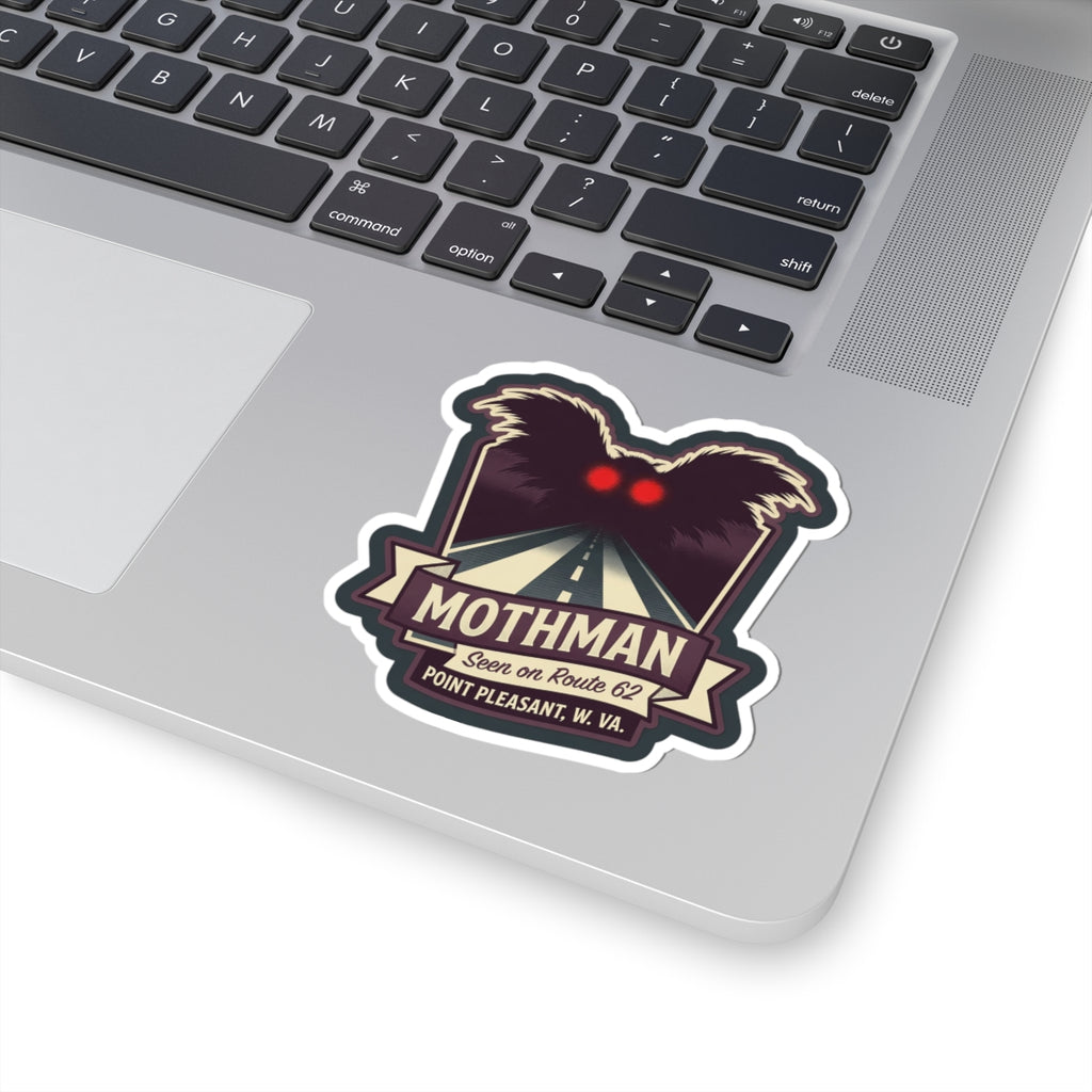 Kiss-cut Mothman sticker on a laptop lid, with red eyes and Route 62 road artwork