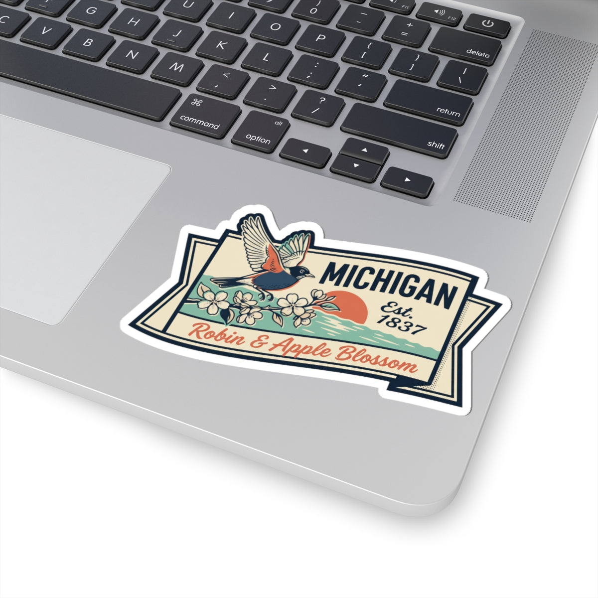 Michigan vintage sticker on laptop keyboard with robin, apple blossoms, and “Est. 1837”