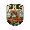 Shield-shaped Arches Utah kiss-cut sticker with Delicate Arch scene and UT AH text at the bottom