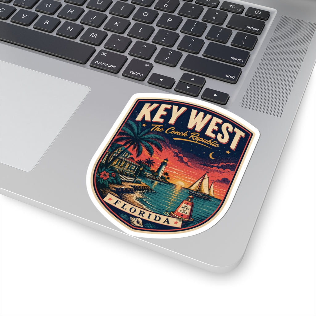 Key West luggage tag sticker on laptop lid, lighthouse and sailboat scene with 'KEY WEST' text