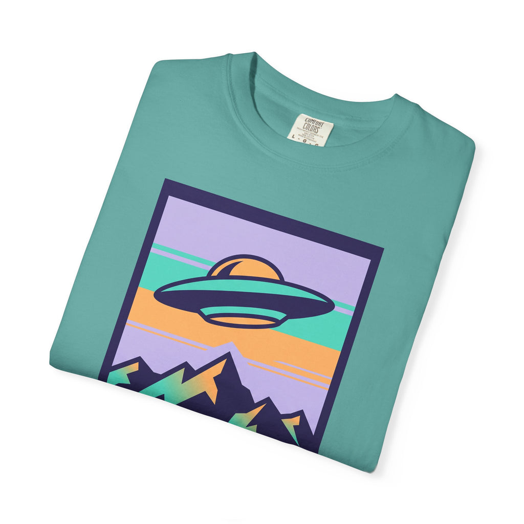 Teal T-shirt with square UFO and mountain landscape graphic on front.