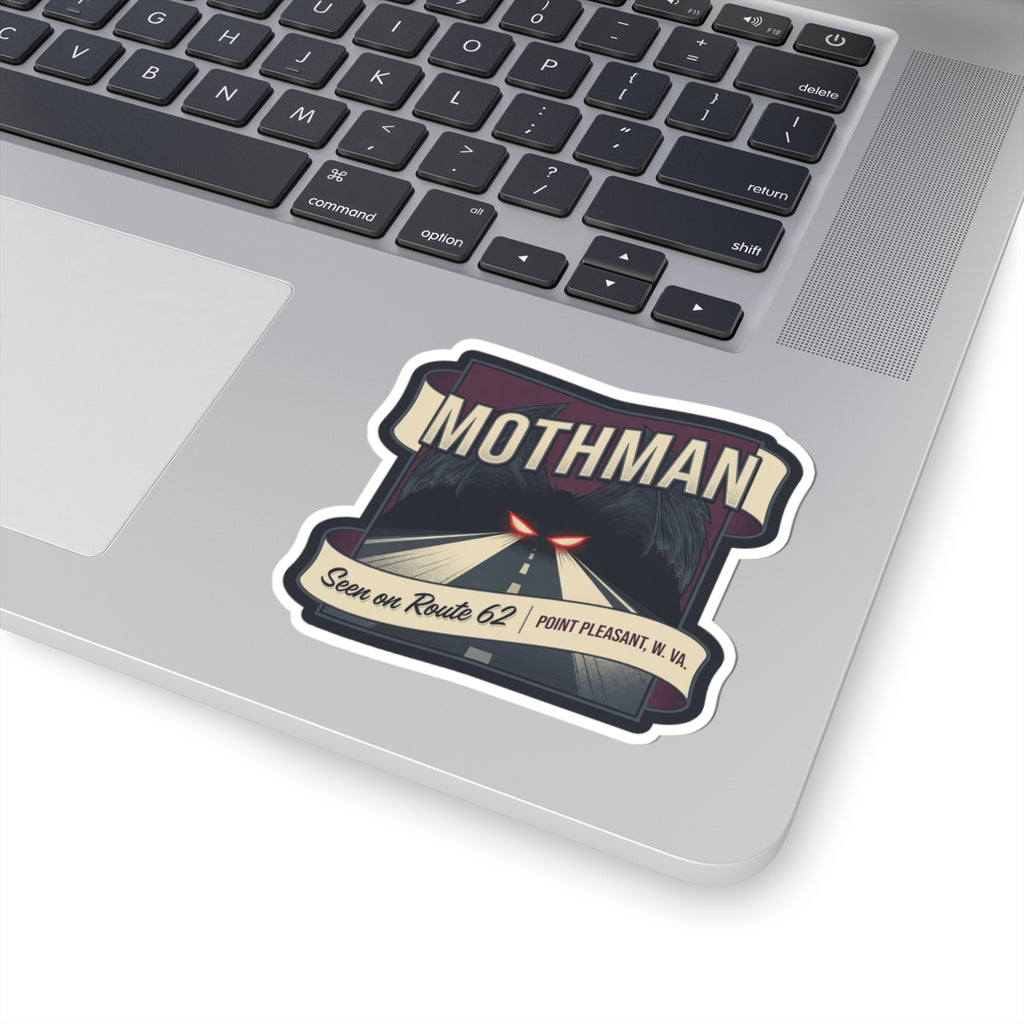 Mothman die-cut sticker on a laptop keyboard: road scene, red eyes, Route 62, Point Pleasant W.Va.