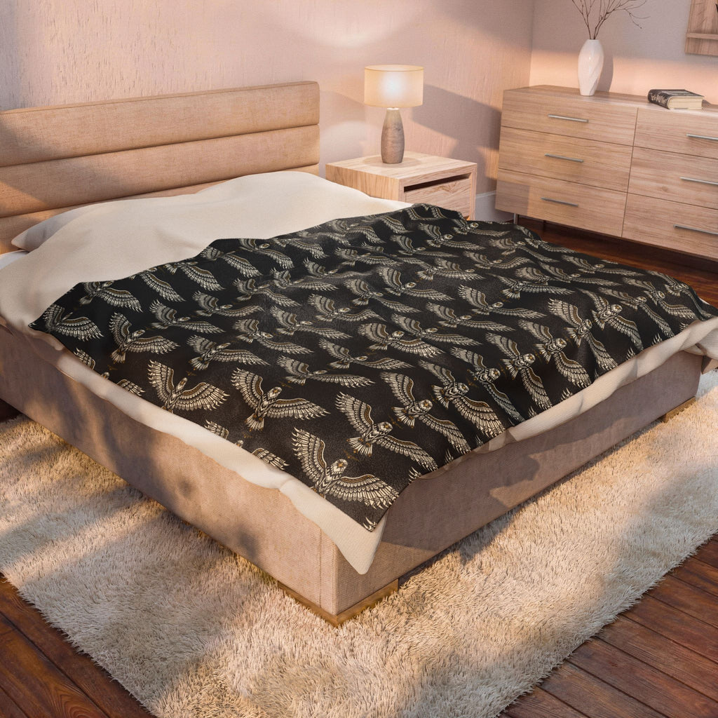 Velveteen plush blanket on bed with dark base and gold winged skull pattern