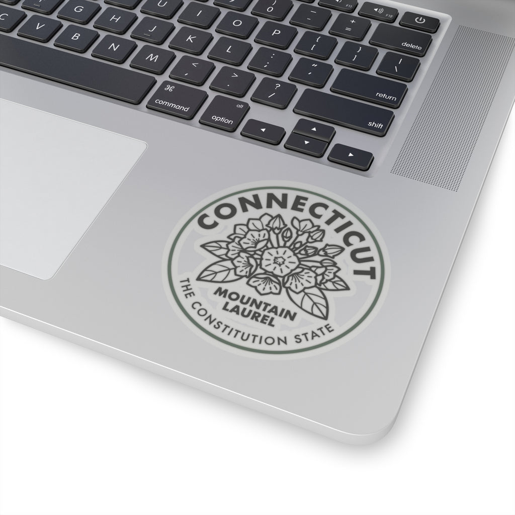 Round green-bordered Connecticut seal sticker on a laptop lid with mountain laurel art