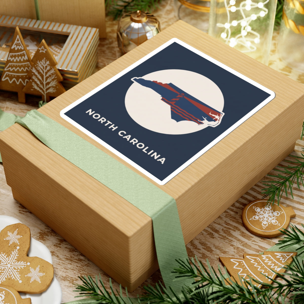 North Carolina state kiss-cut sticker on wrapped gift, navy square with map and text
