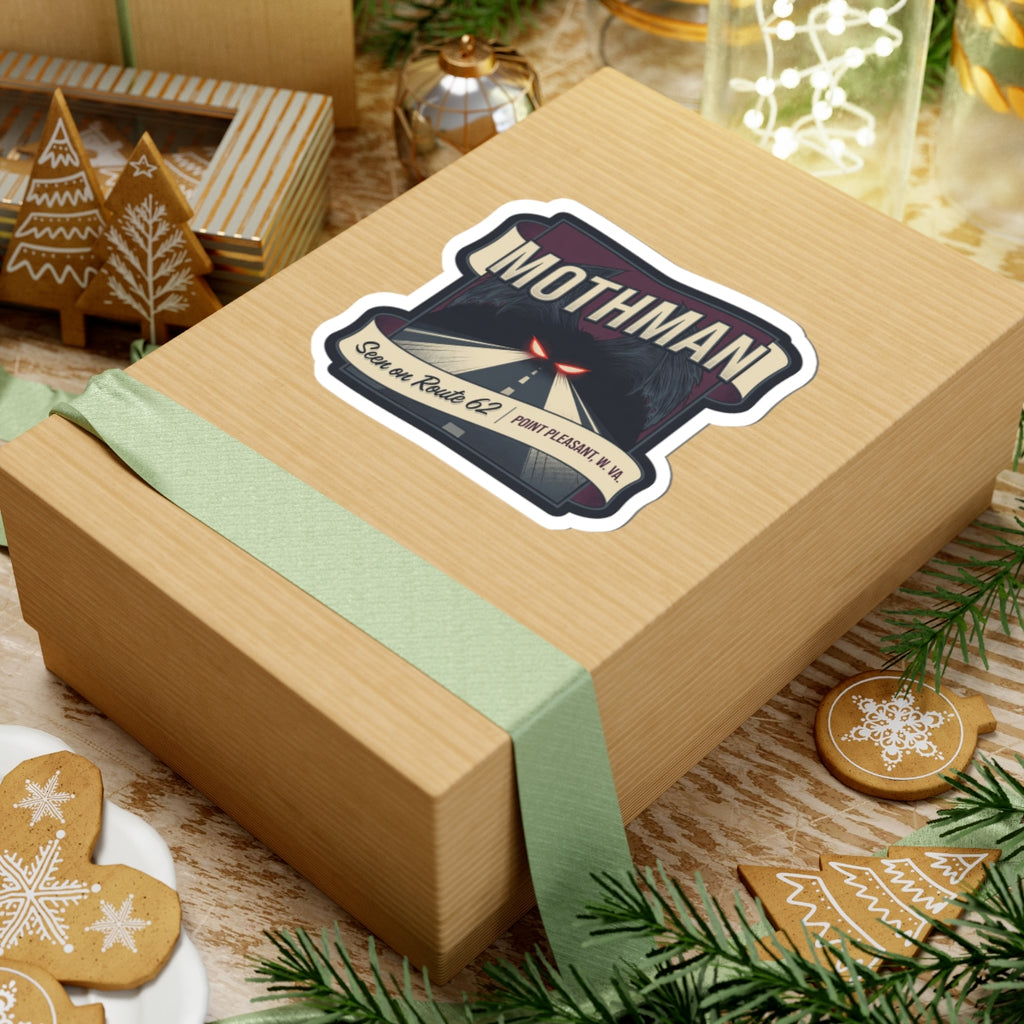 Mothman sticker on gift box: night road art, red glowing eyes, “Seen on Route 62,” Point Pleasant W.Va.