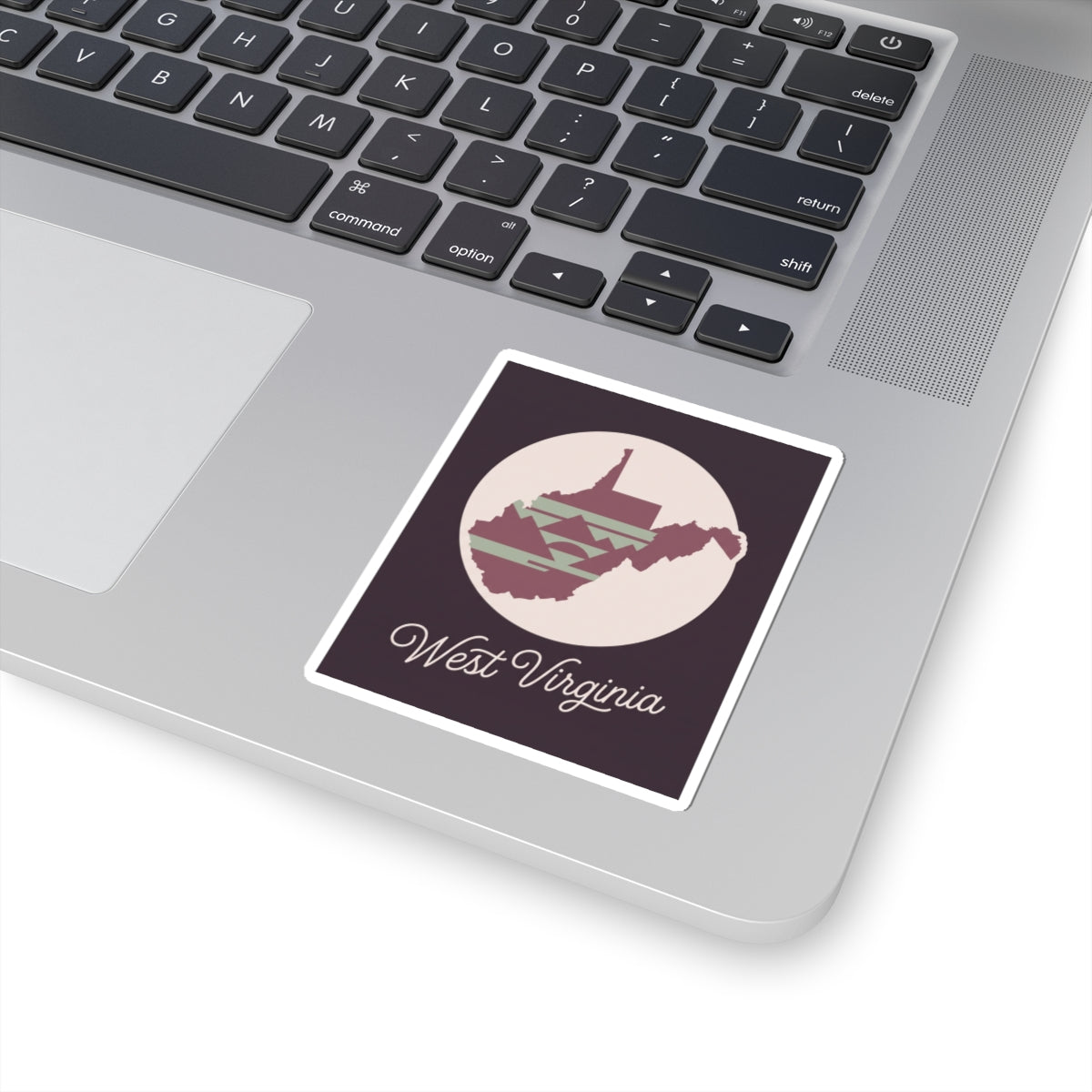 Square West Virginia decal on laptop keyboard: circular state graphic with “West Virginia” script.