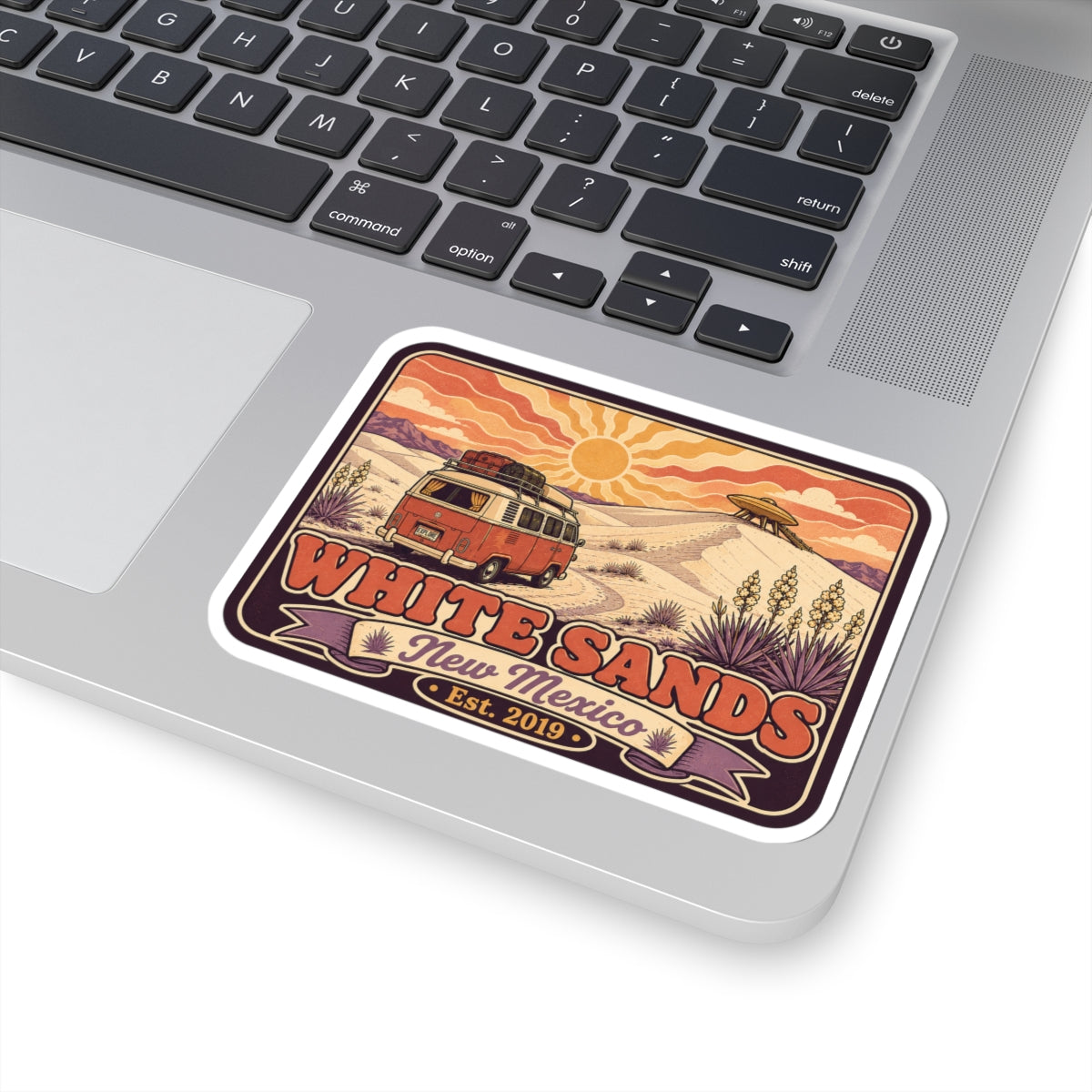 Rounded rectangle sticker on laptop; vintage camper van and White Sands "Est. 2019"