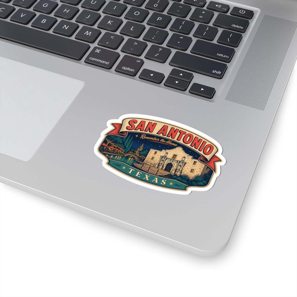 San Antonio luggage tag sticker on a laptop keyboard, Alamo scene with TEXAS ribbon