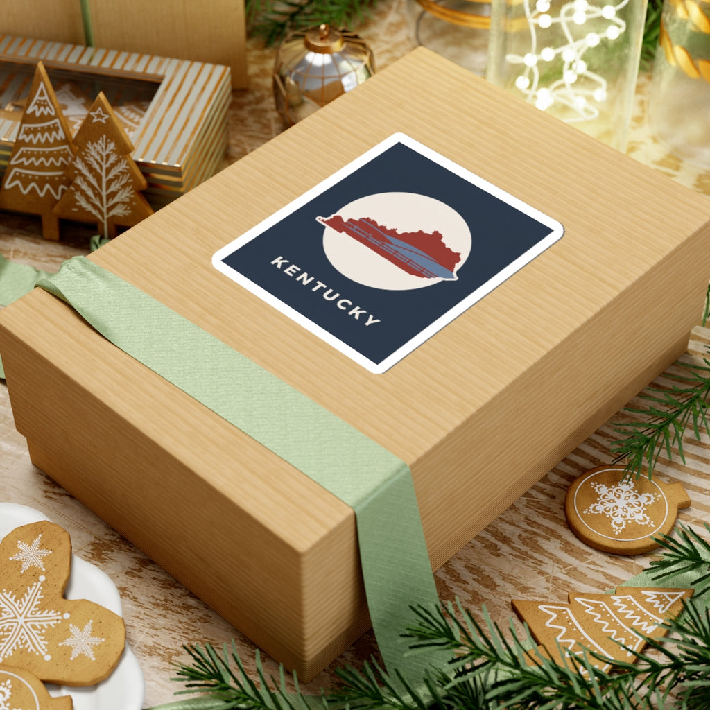 Kentucky travel decal sticker on wrapped gift: navy square with red Kentucky silhouette and KENTUCKY