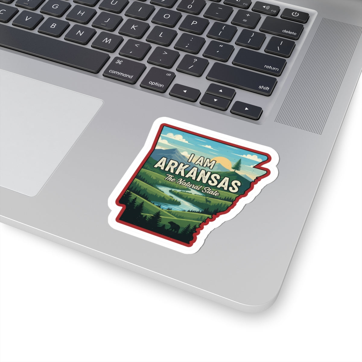 I AM ARKANSAS sticker on laptop keyboard, illustrated state outline with “The Natural State”