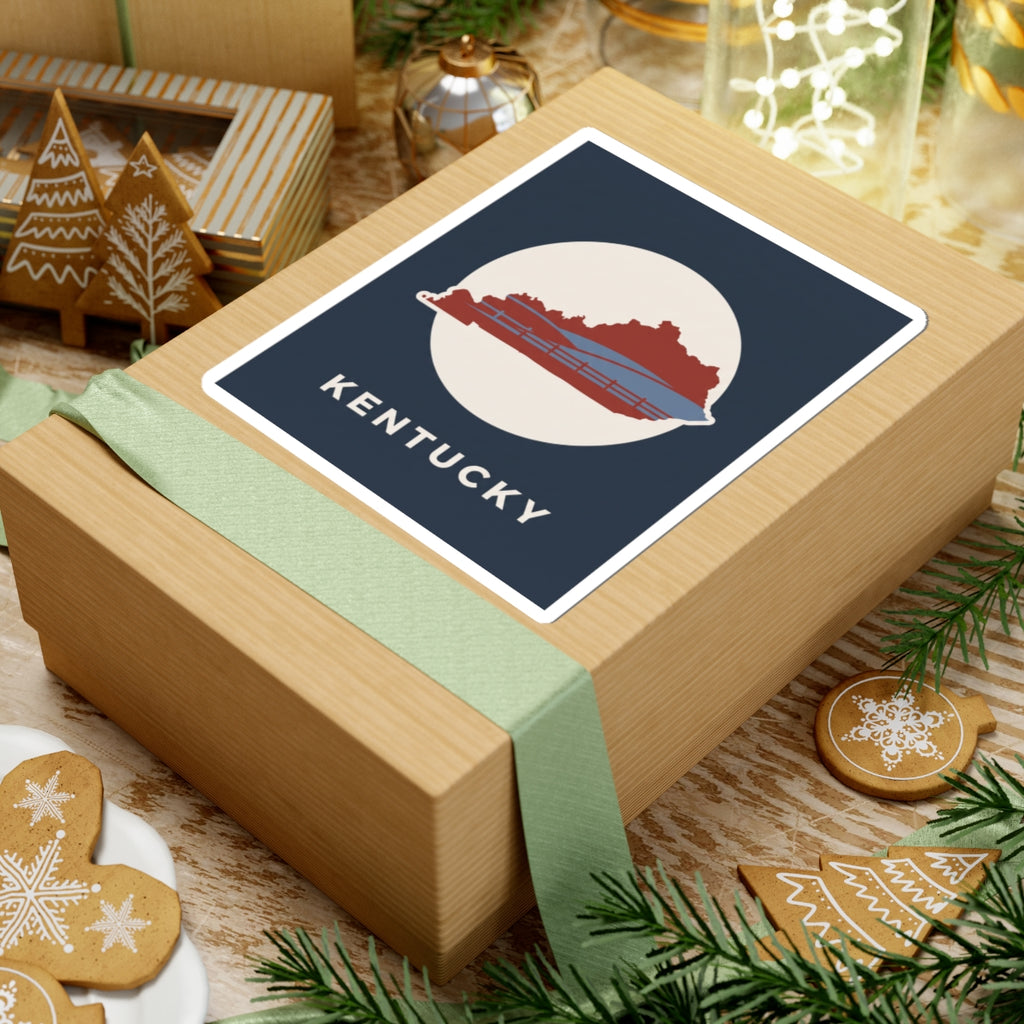 Kentucky travel decal sticker on gift box: navy square with red state outline, bridge, KENTUCKY