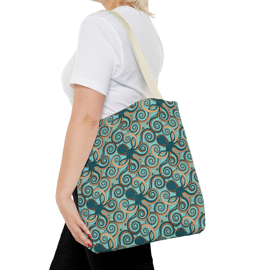 Teal octopus swirl tote bag with rope handles, side view on person.