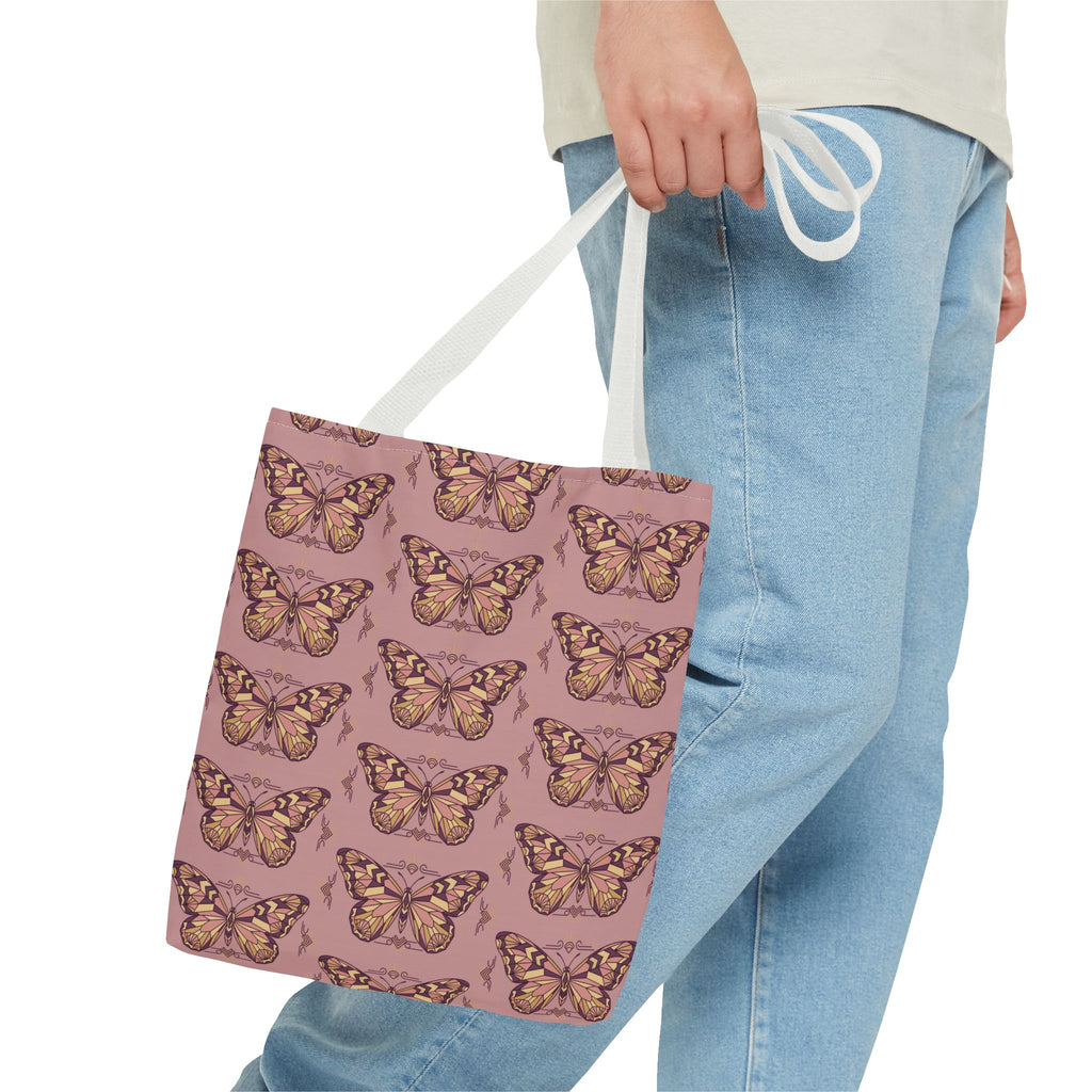 Butterfly-pattern tote bag in pink with white handles, held at the side