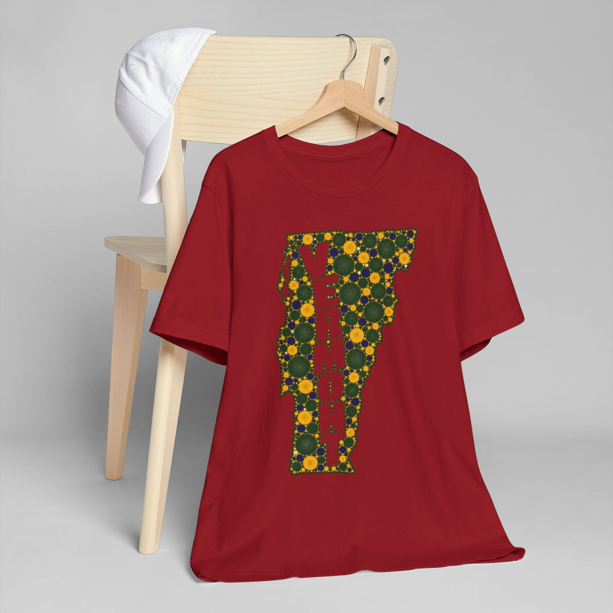 Red graphic t-shirt featuring a floral Vermont map outline with vertical "VERMONT" lettering.