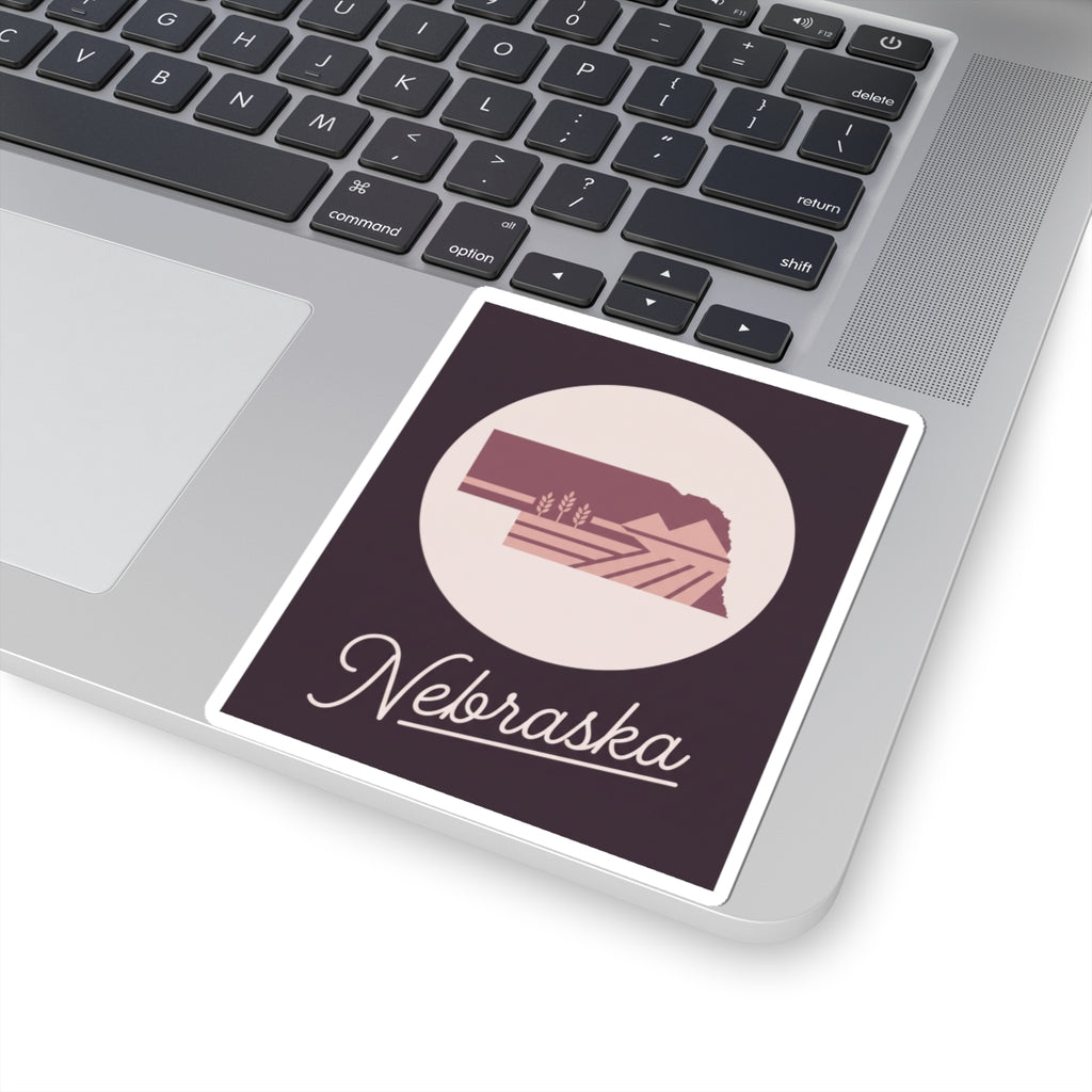 Nebraska square decal on laptop keyboard, circular farmland emblem with cursive Nebraska text