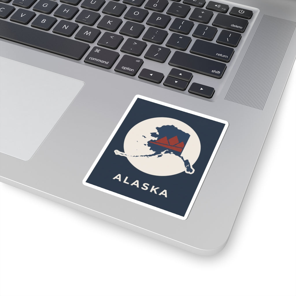 Square Alaska map badge sticker on a laptop, retro mountain in red and navy on cream