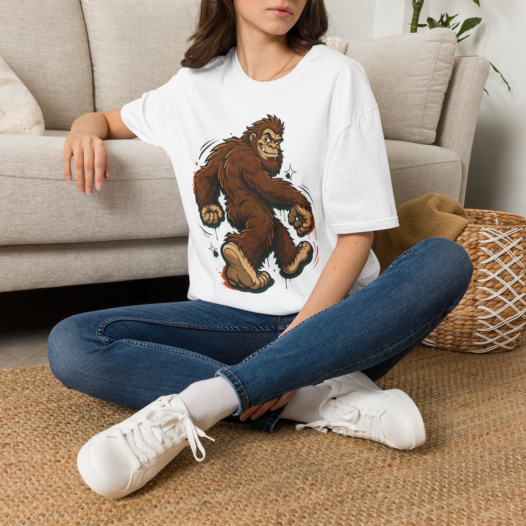 White crewneck t-shirt with brown bigfoot cartoon graphic, worn by a person
