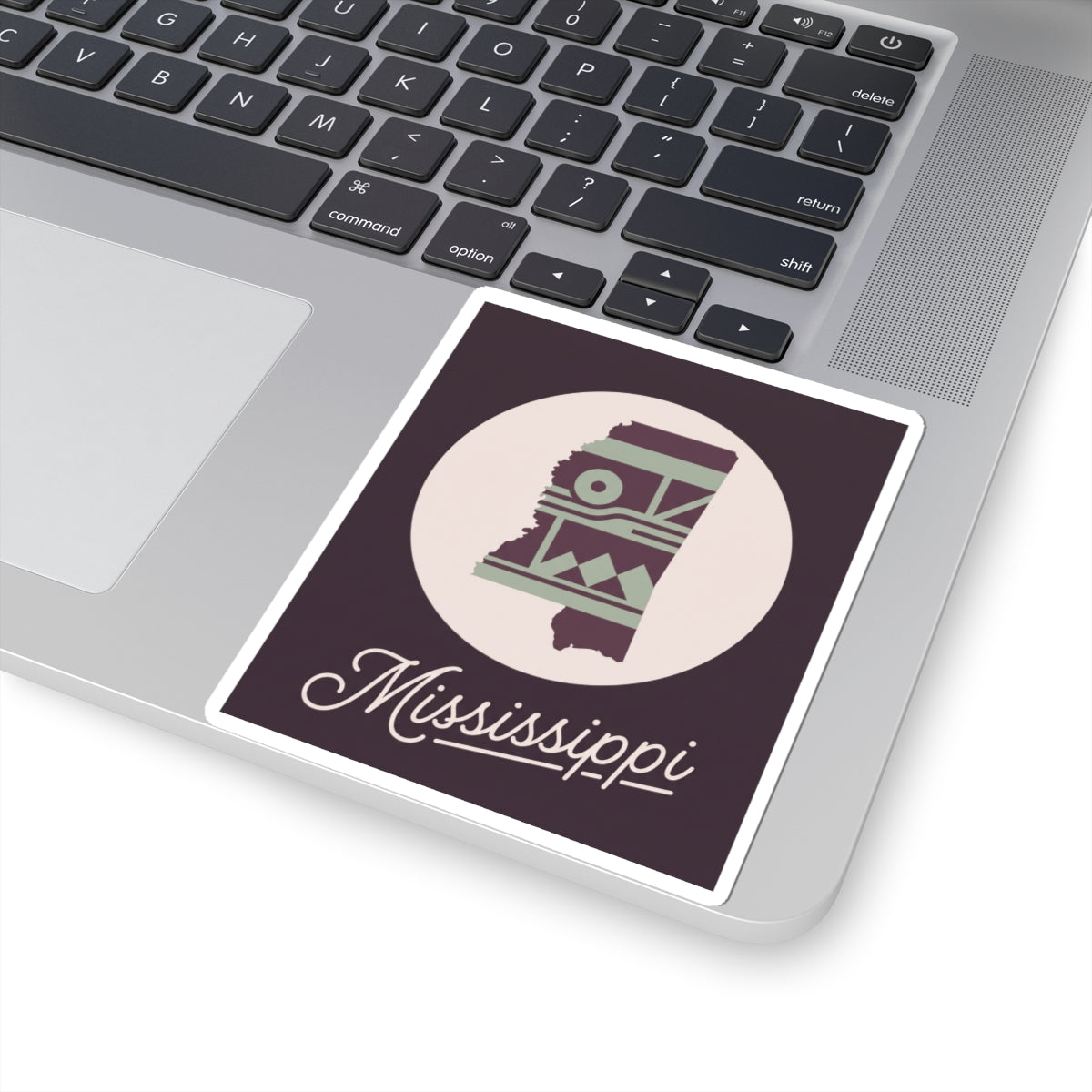 Mississippi state sticker decal on laptop keyboard, purple square border with circular emblem and script