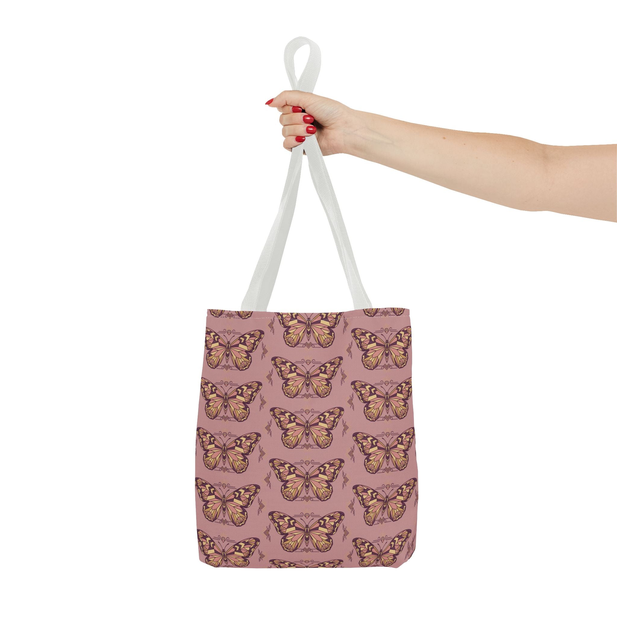 Pink butterfly print tote bag with light handles, held by one hand.