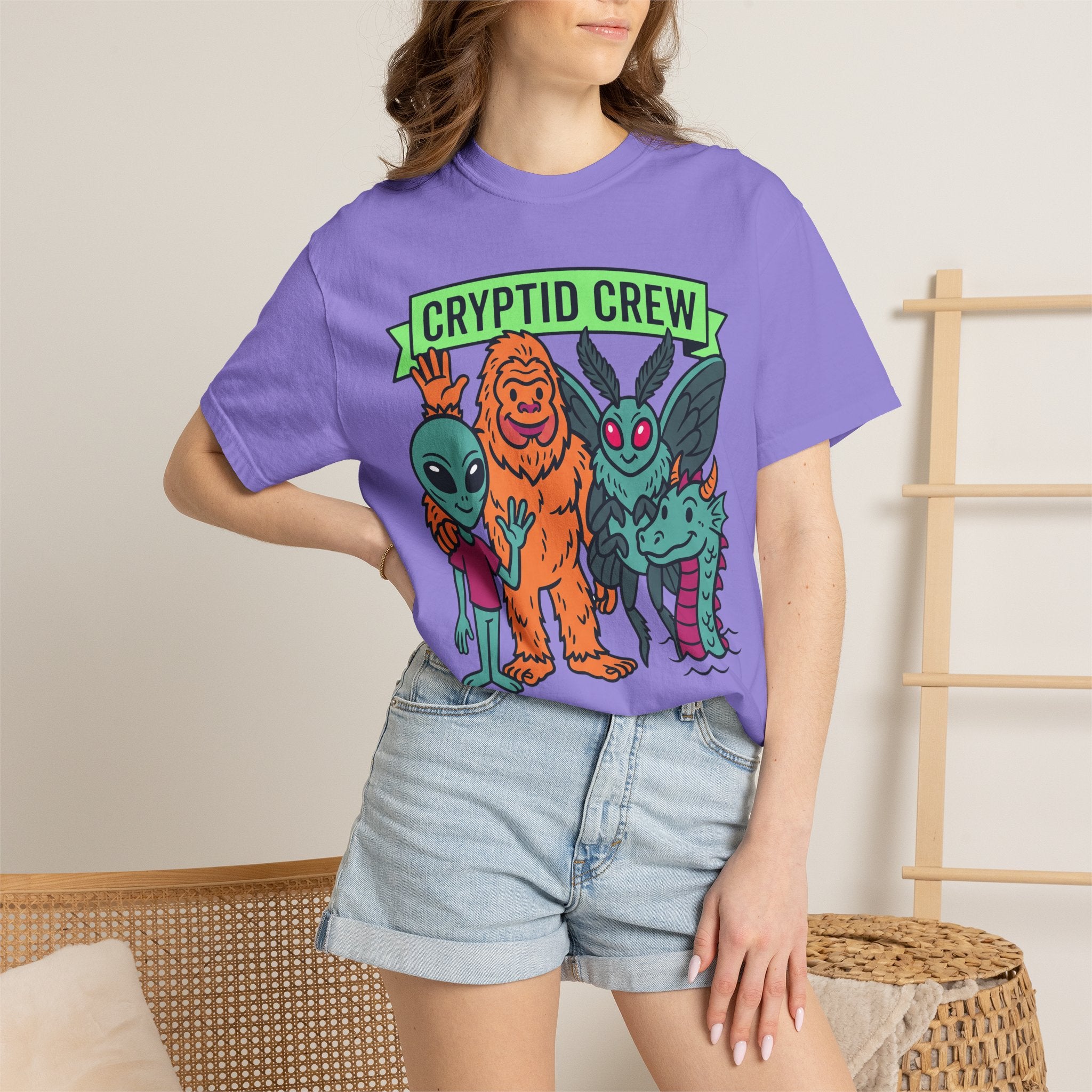 Purple Cryptid Crew T-shirt with green banner graphic worn by a woman