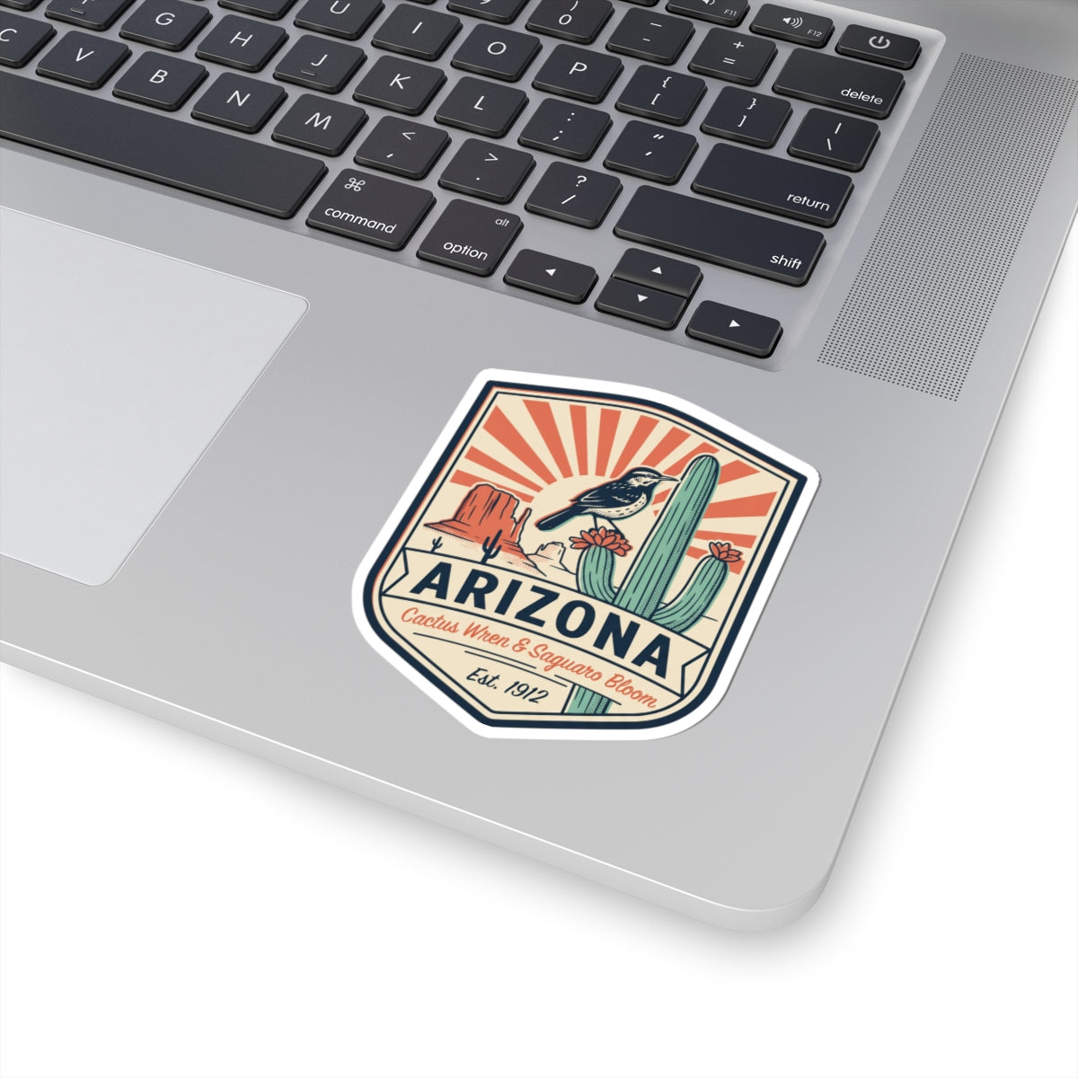 Arizona sticker badge on a laptop lid, cactus wren and saguaro bloom design, Est. 1912.