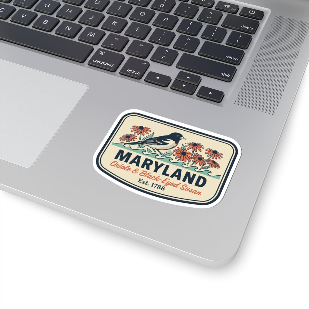 Maryland sticker on a laptop keyboard, rounded badge design with bird, flowers, and “Est. 1788”