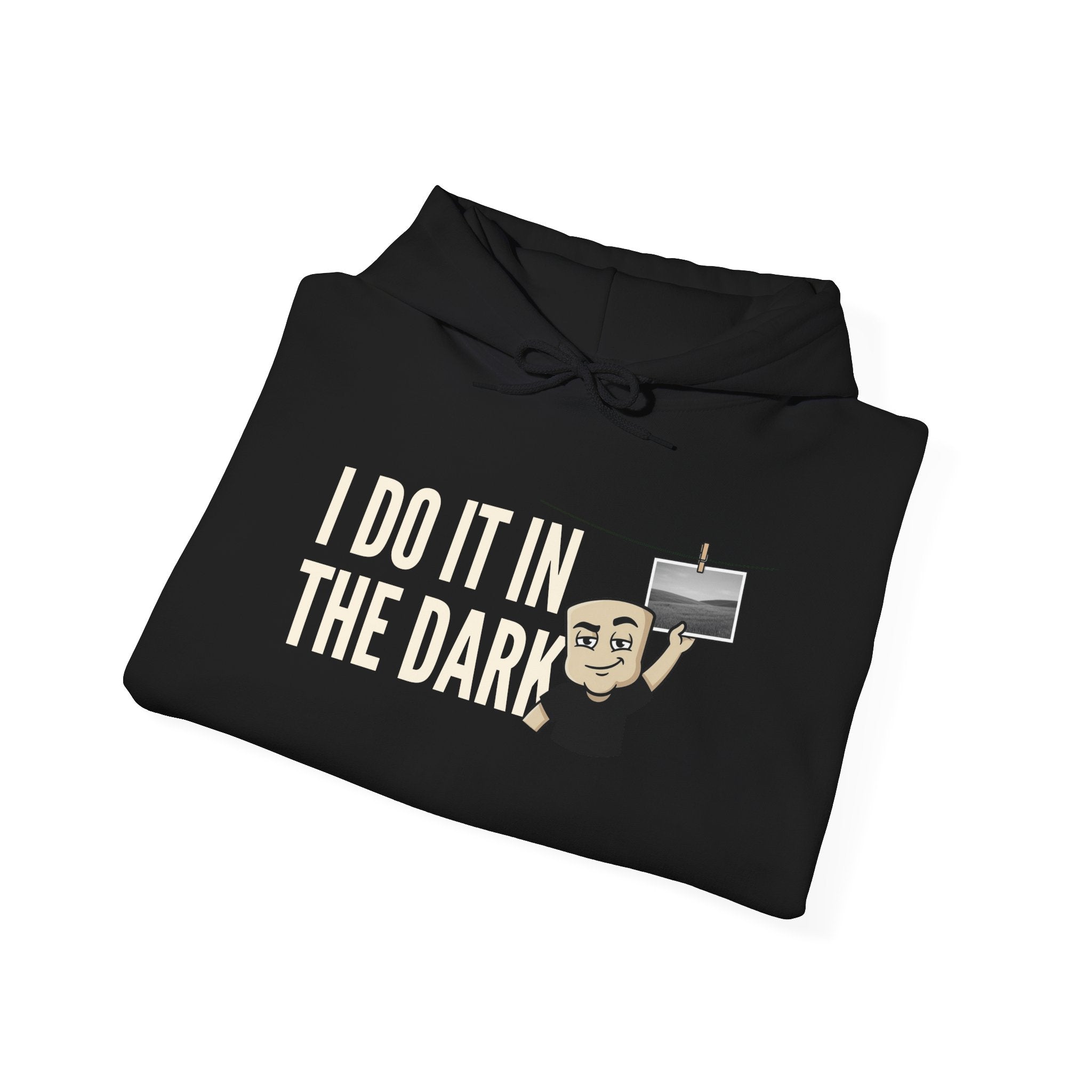 Black hoodie folded with front “I DO IT IN THE DARK” graphic and small cross icon