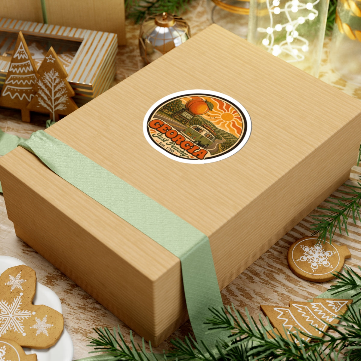 Round vinyl sticker on tan gift box, featuring Georgia Just Peachy orange peaches and green van