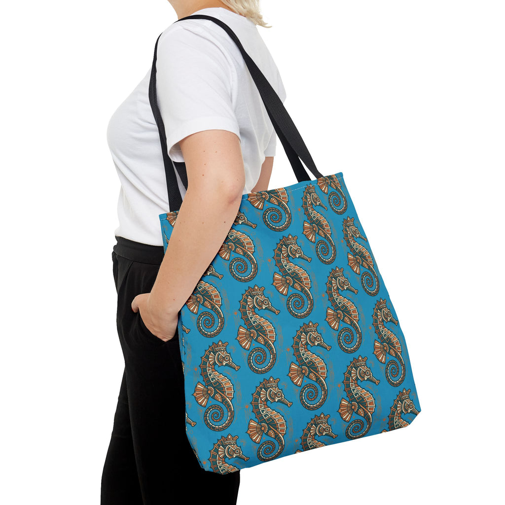 Tote bag side view in blue with all-over seahorse pattern and black straps