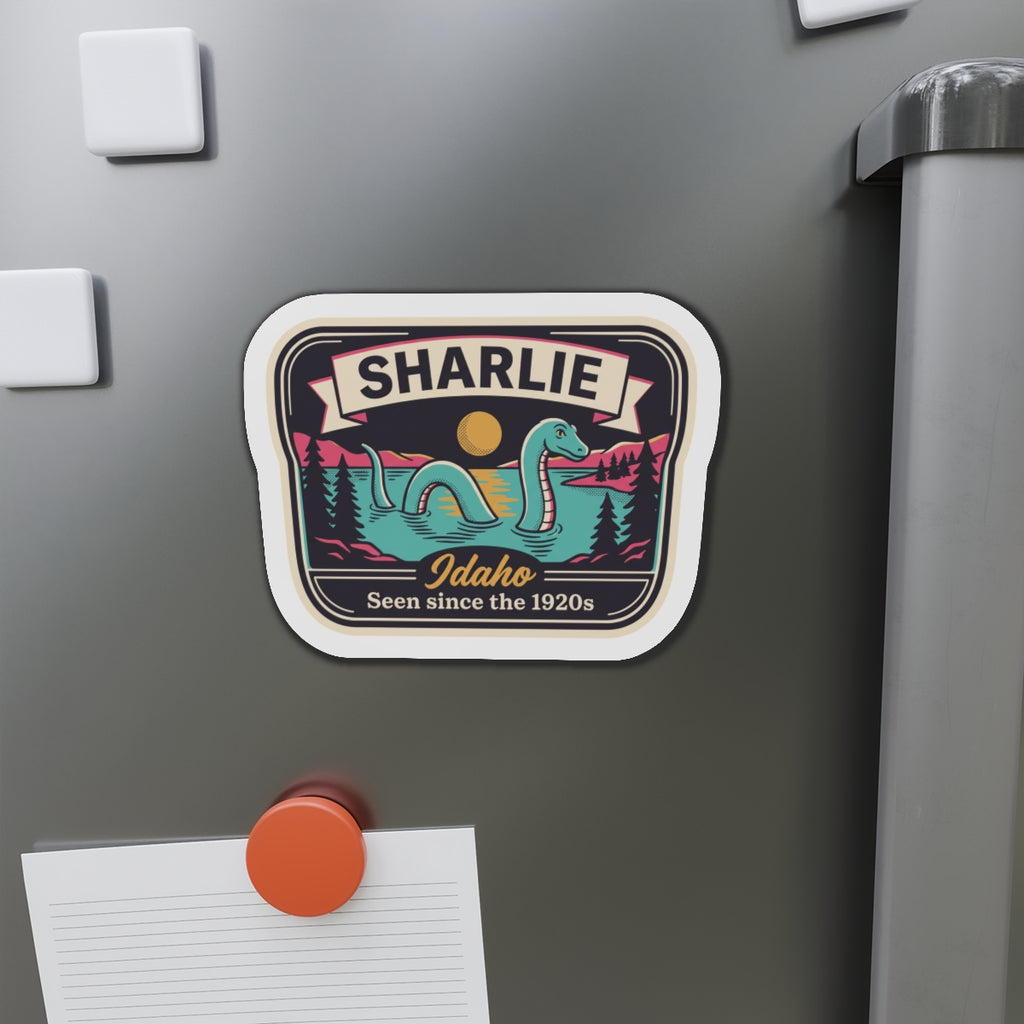 Rounded die-cut magnet showing SHARLIE Idaho badge with teal sea-serpent illustration