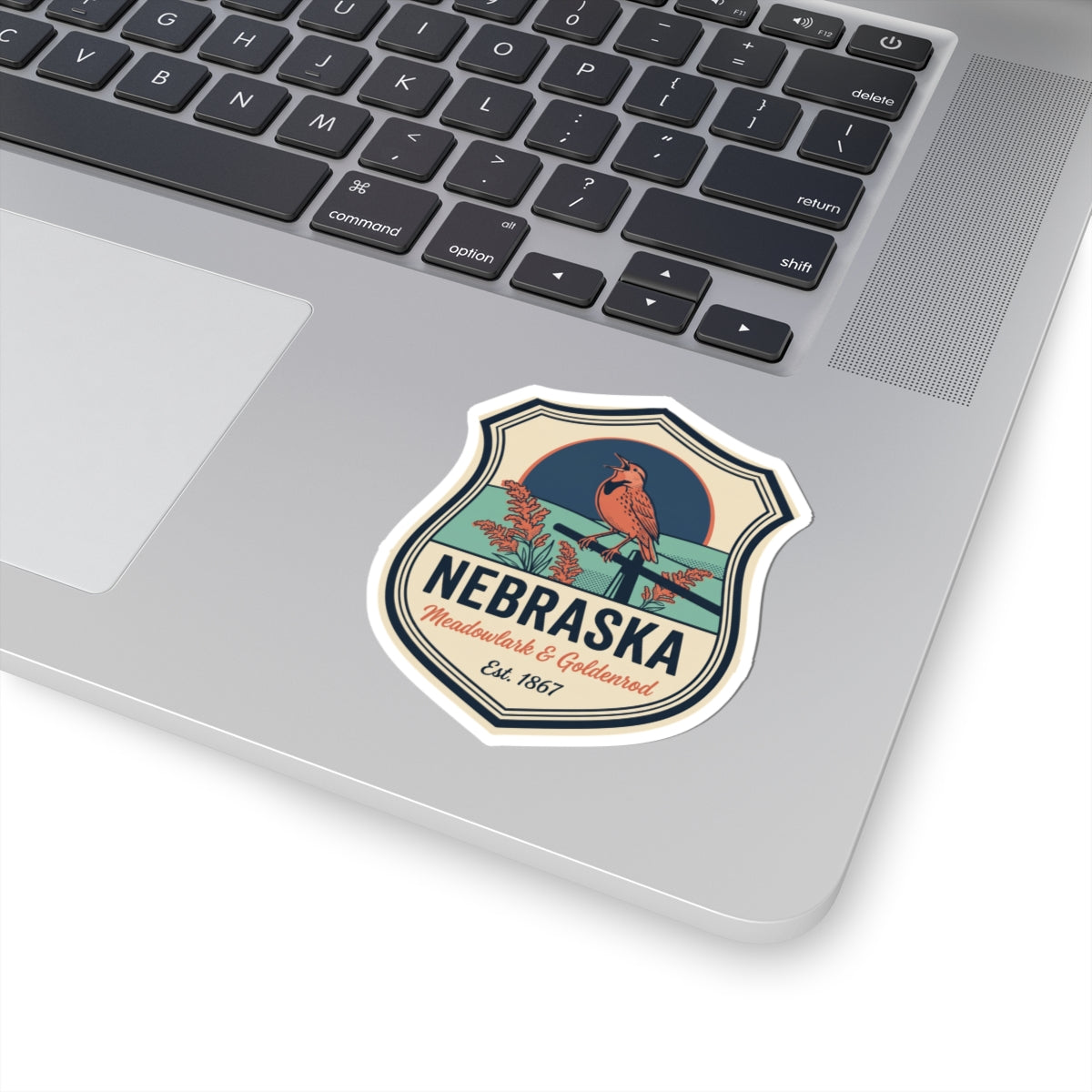 Nebraska vintage badge sticker on a laptop palmrest, meadowlark & goldenrod, Est. 1867