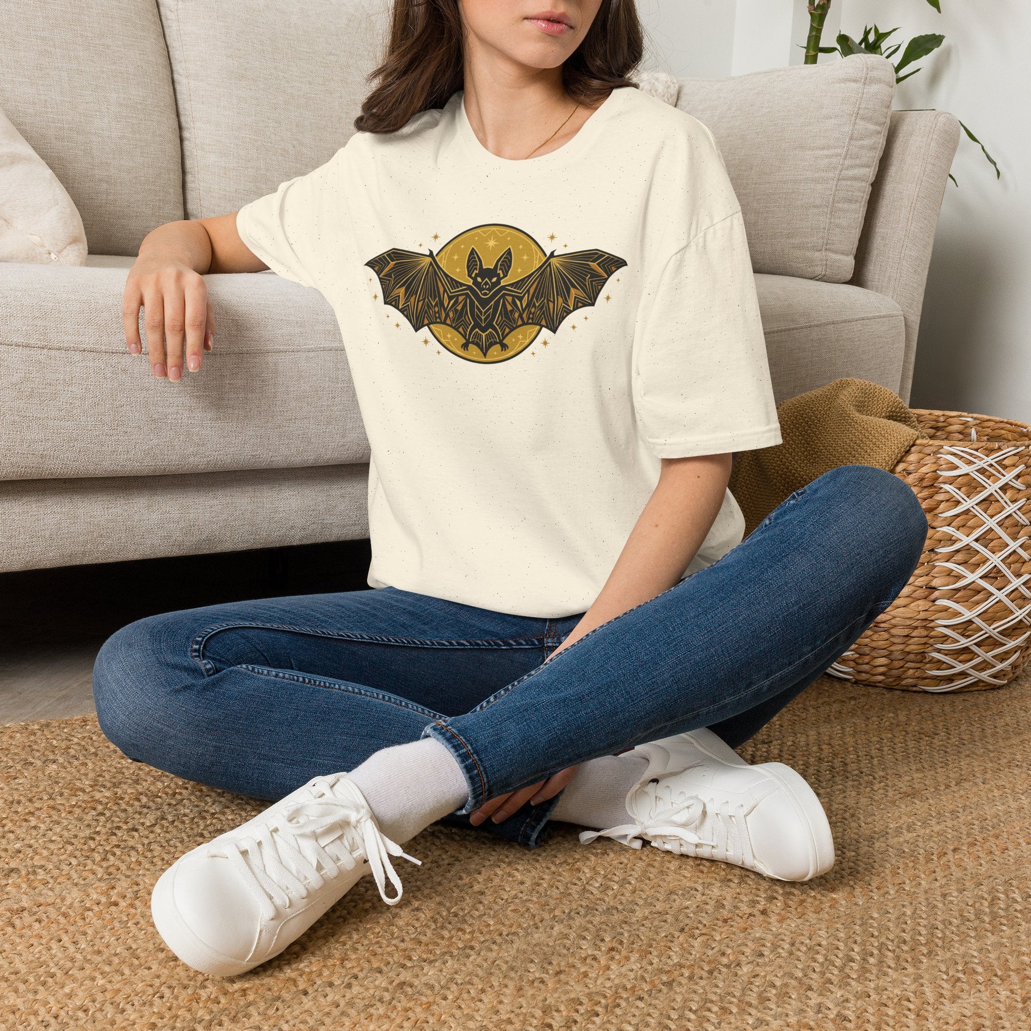 Off-white T-shirt with gold bat-and-moon graphic on the chest