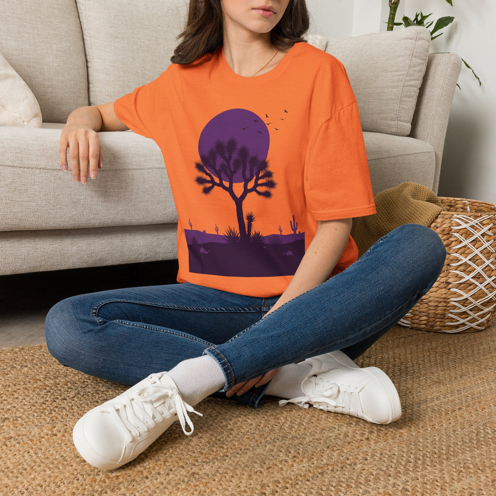 Orange T-shirt with purple moon desert tree silhouette and birds graphic on chest.