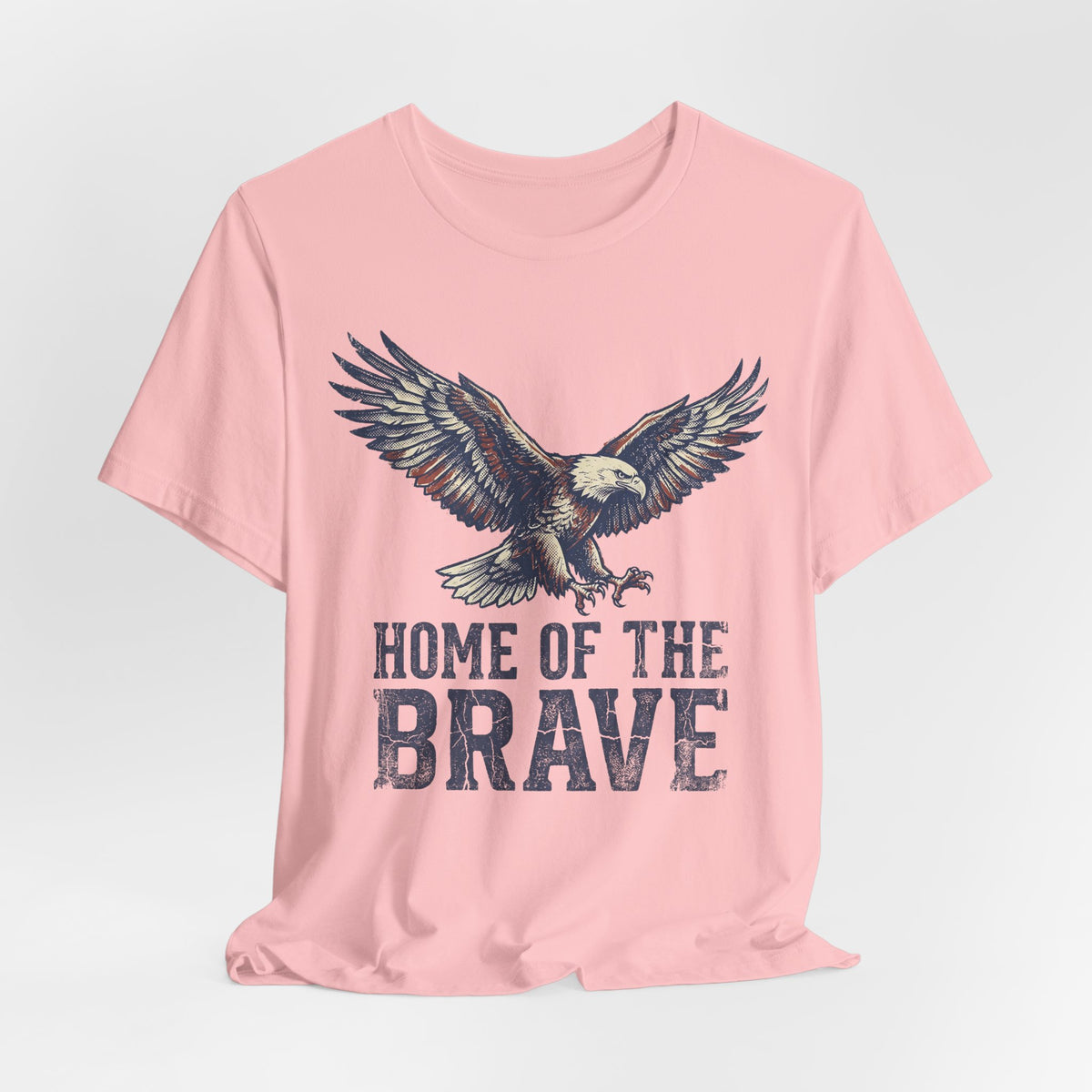 Light pink crew-neck T-shirt with eagle graphic and “HOME OF THE BRAVE” text