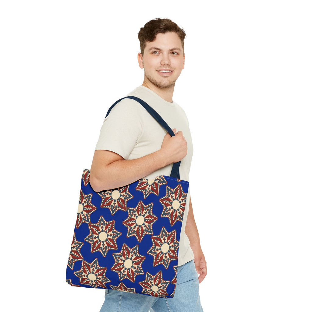 Starburst floral tote bag in blue with red and cream star motifs, worn on shoulder.