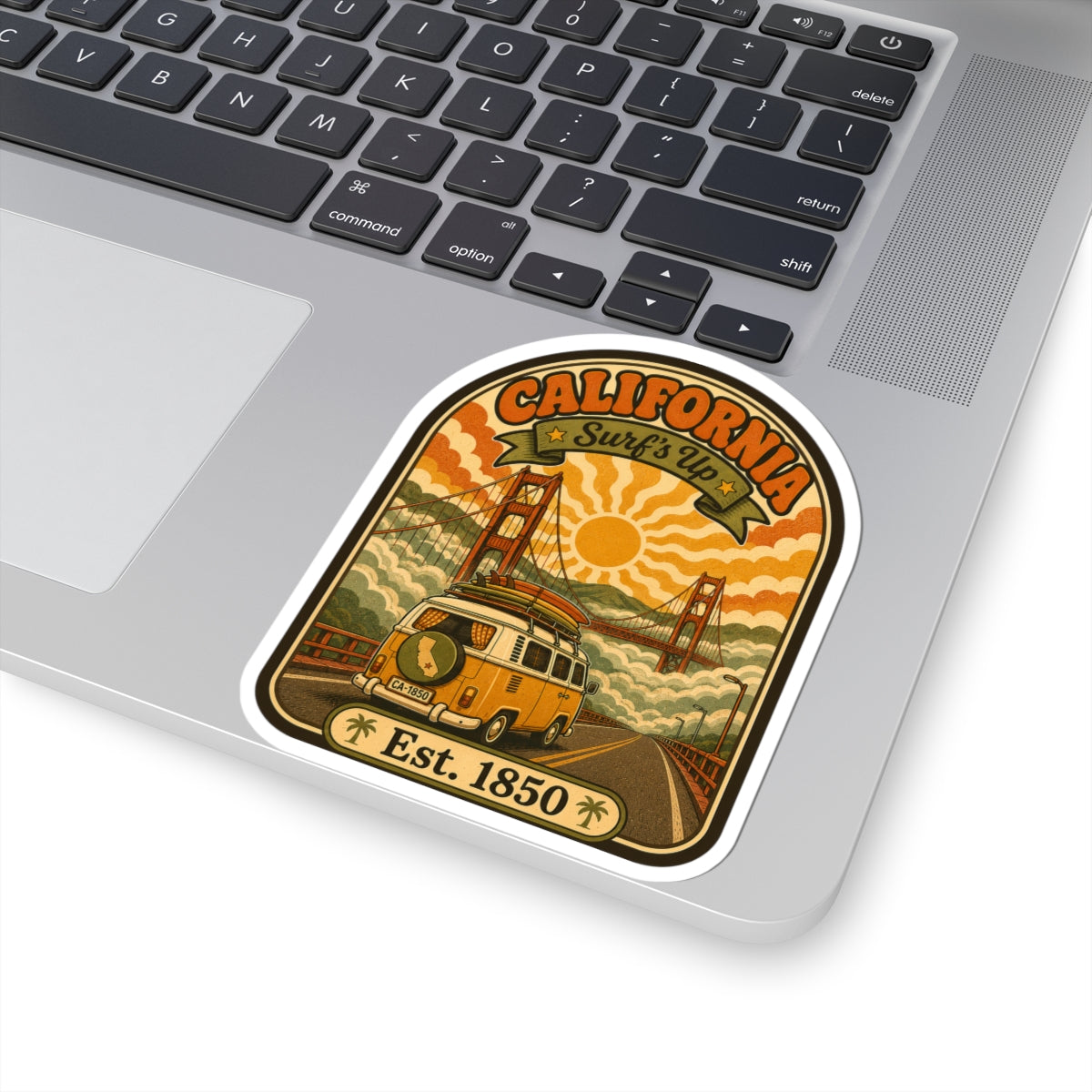 California surf van sticker on a laptop lid, featuring bridge scene and “Est. 1850”.