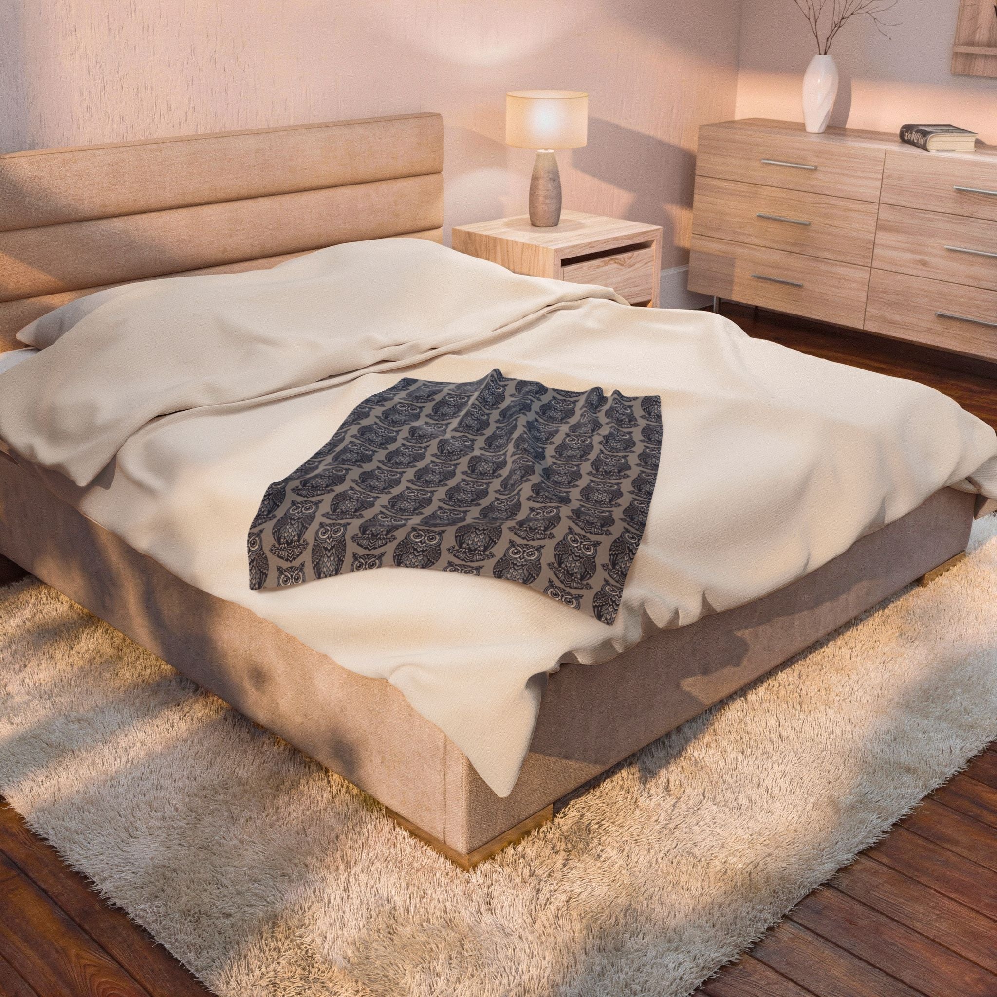Blue owl-pattern plush blanket partially folded on bed with repeating owl prints